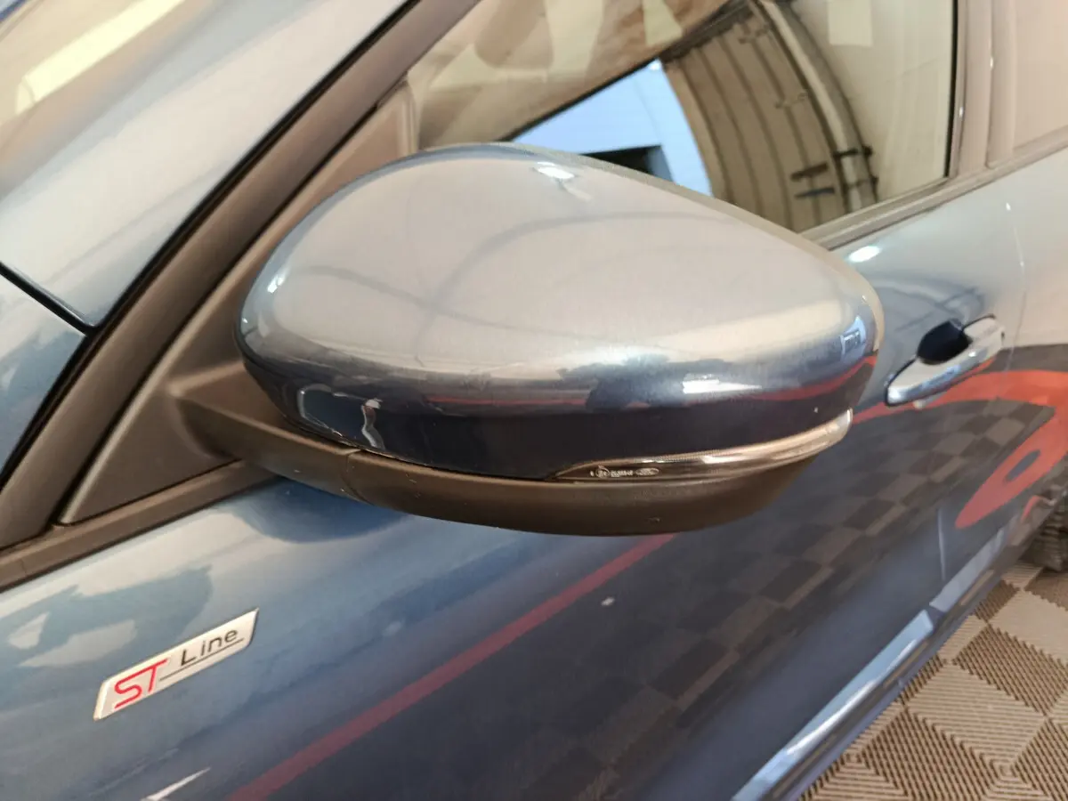 Gros plan sur le rétroviseur côté gauche bleu du Ford Kuga 2024 ST Line avec logo ST visible sur la portière.