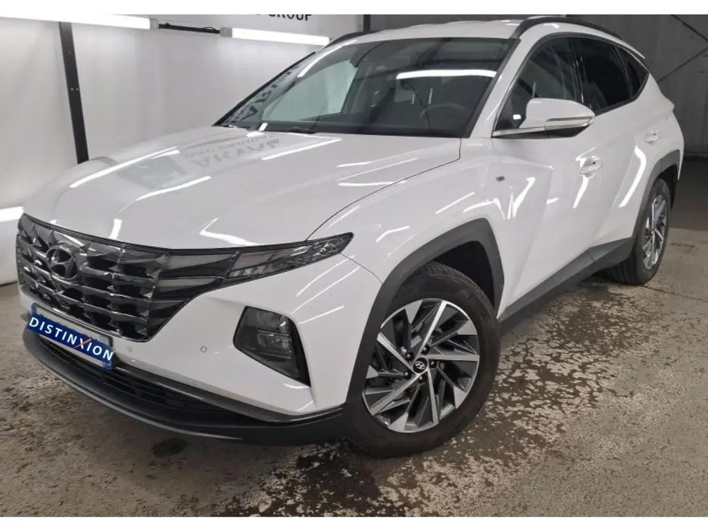 Hyundai Tucson blanc vu en 3/4 avant droit, avec calandre noire distinctive et jantes alliage modernes.