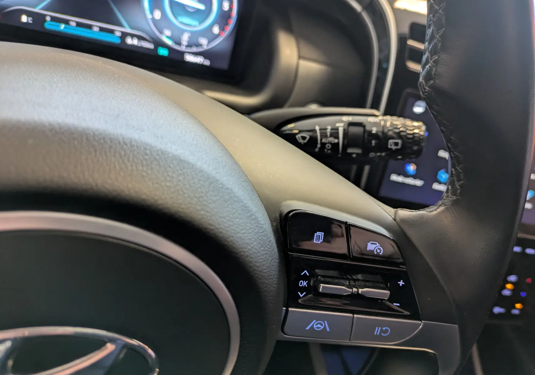 Gros plan sur les commandes au volant du Hyundai Tucson blanc 2021, avec écran digital et régulateur de vitesse.