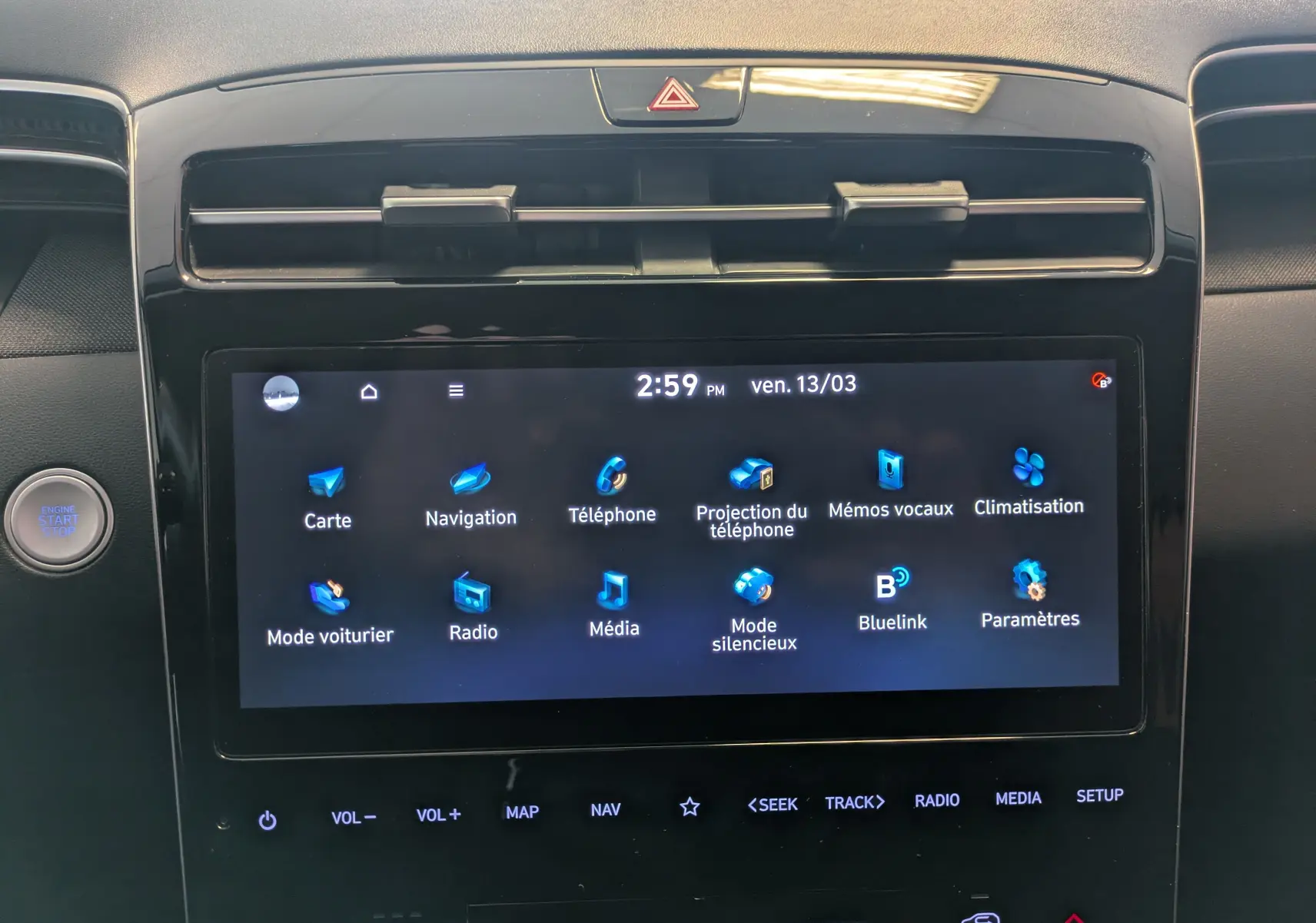 Vue rapprochée de l’écran tactile central du Hyundai Tucson blanc 2021, affichant les icônes du système de navigation et multimédia.