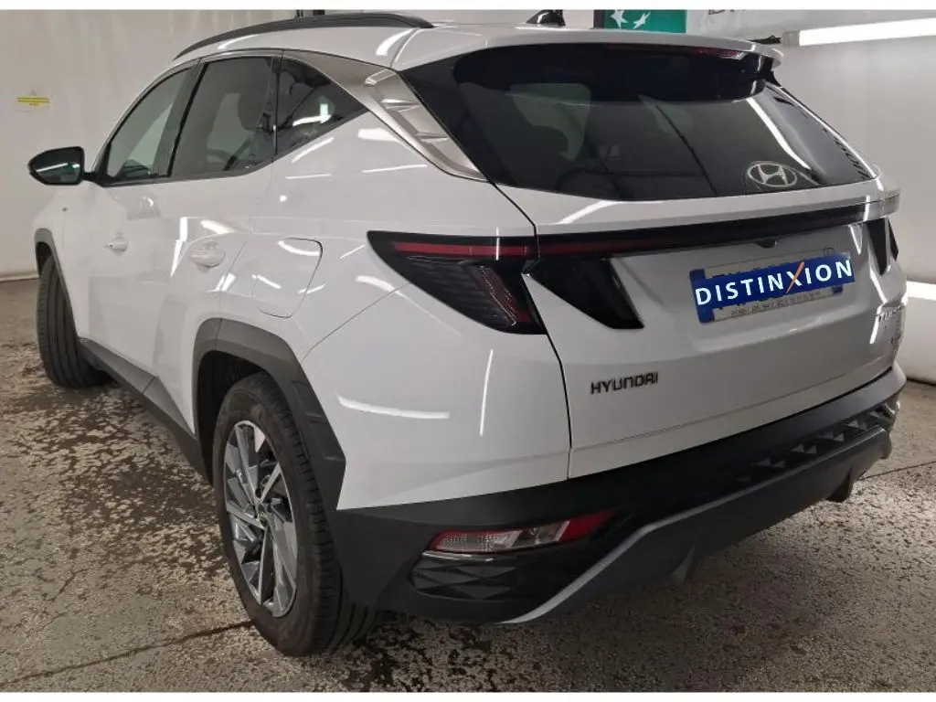 Vue 3/4 arrière droite d'un Hyundai Tucson blanc 2021 avec feux arrière LED et jantes alliage visibles.