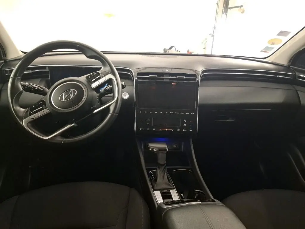 Vue intérieure du tableau de bord noir du Hyundai Tucson 2021 avec volant multifonction et écran tactile central.