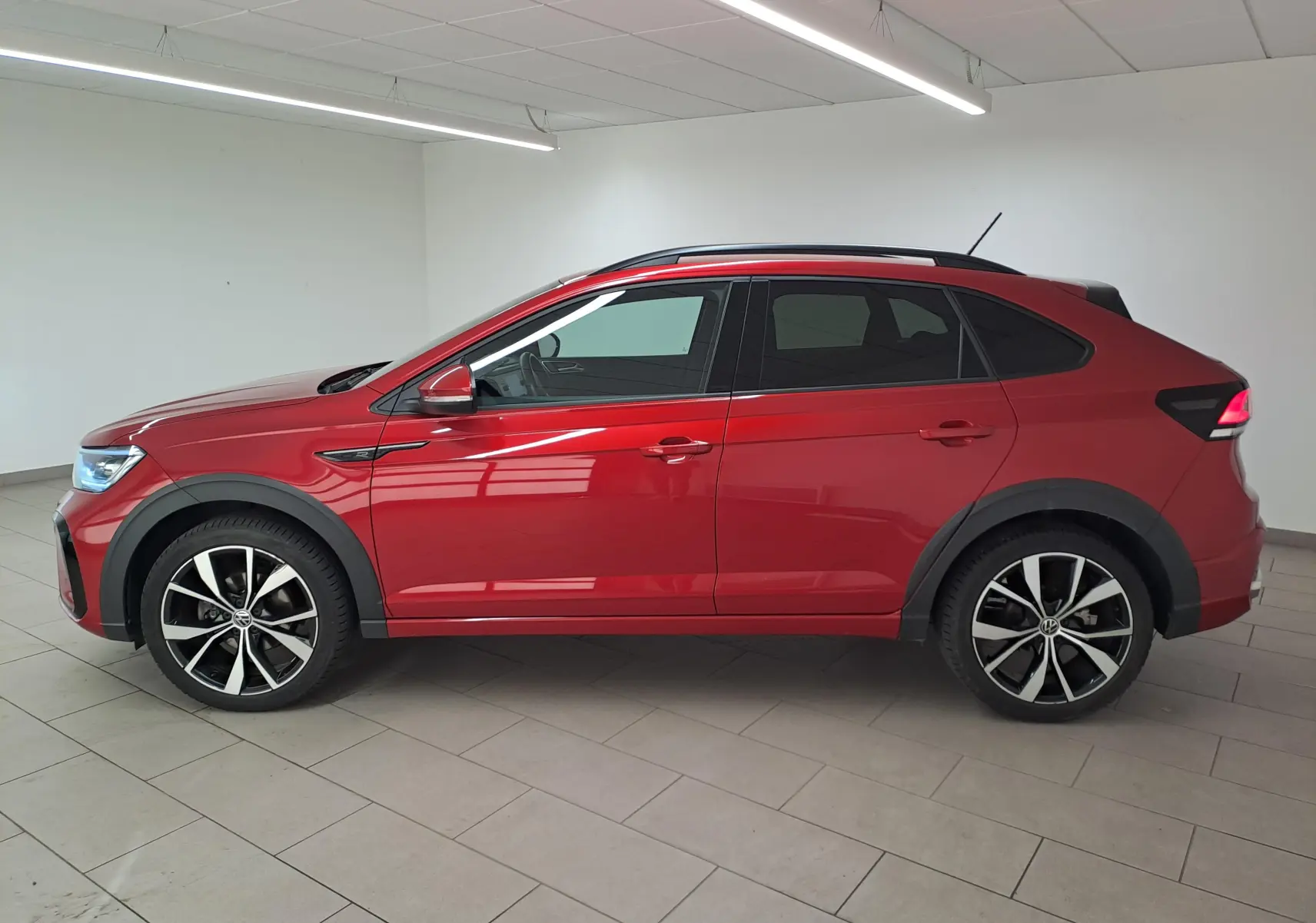 Vue de profil côté gauche d’un Volkswagen Taigo 1.5 TSI 150 DSG7 R-LINE rouge Roi avec jantes alliage noires 18 pouces.