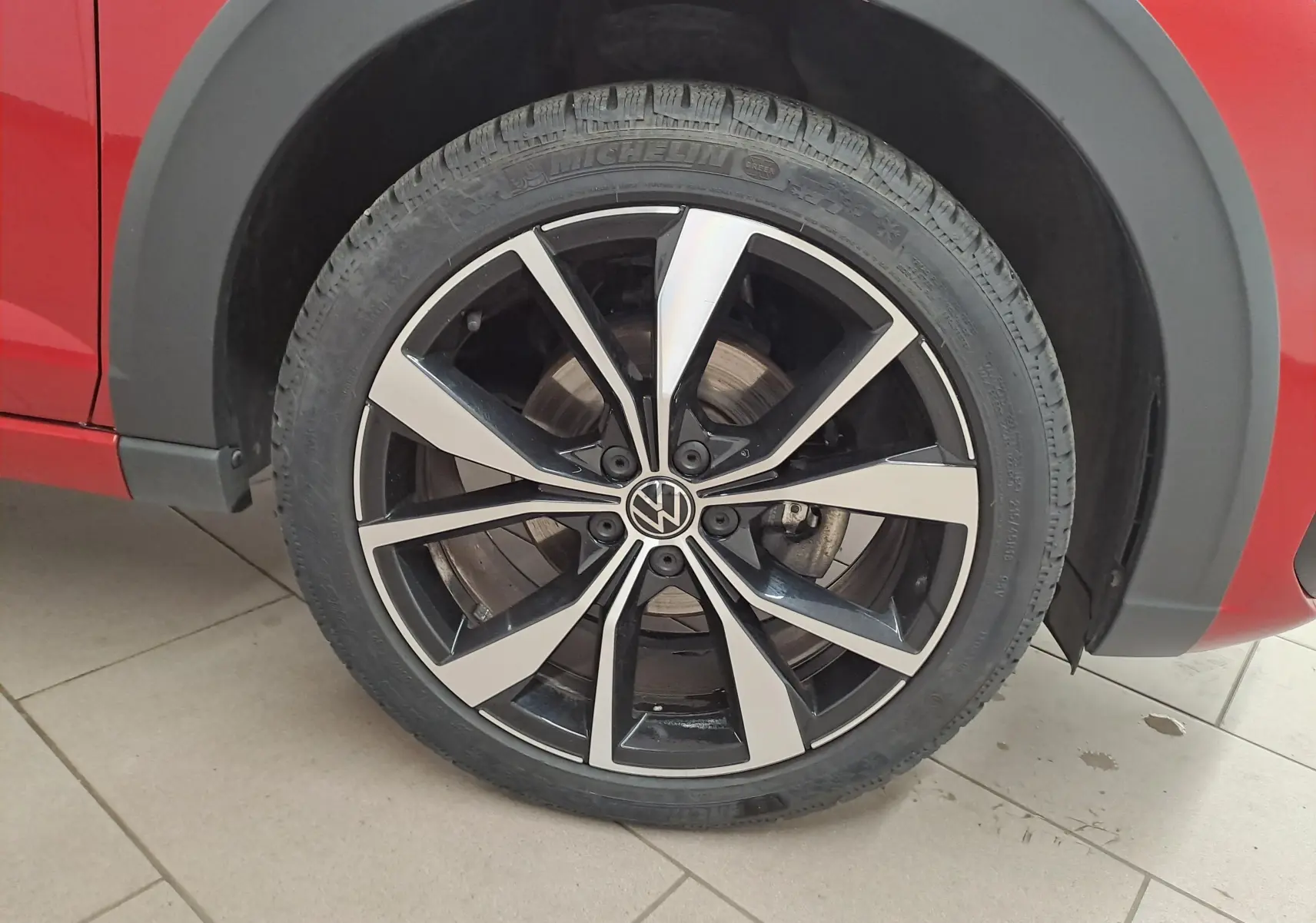 Gros plan sur la jante alliage noire et argentée 18 pouces du côté gauche d’un Volkswagen Taigo Rouge Roi.