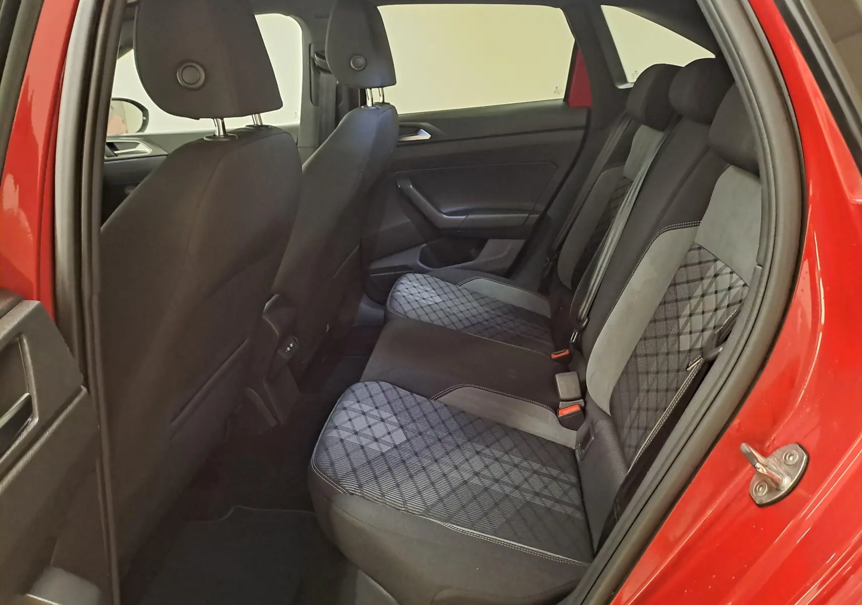 Vue intérieure côté arrière droit du Volkswagen Taigo Rouge Roi 2021, montrant les sièges arrière en tissu noir à motifs.