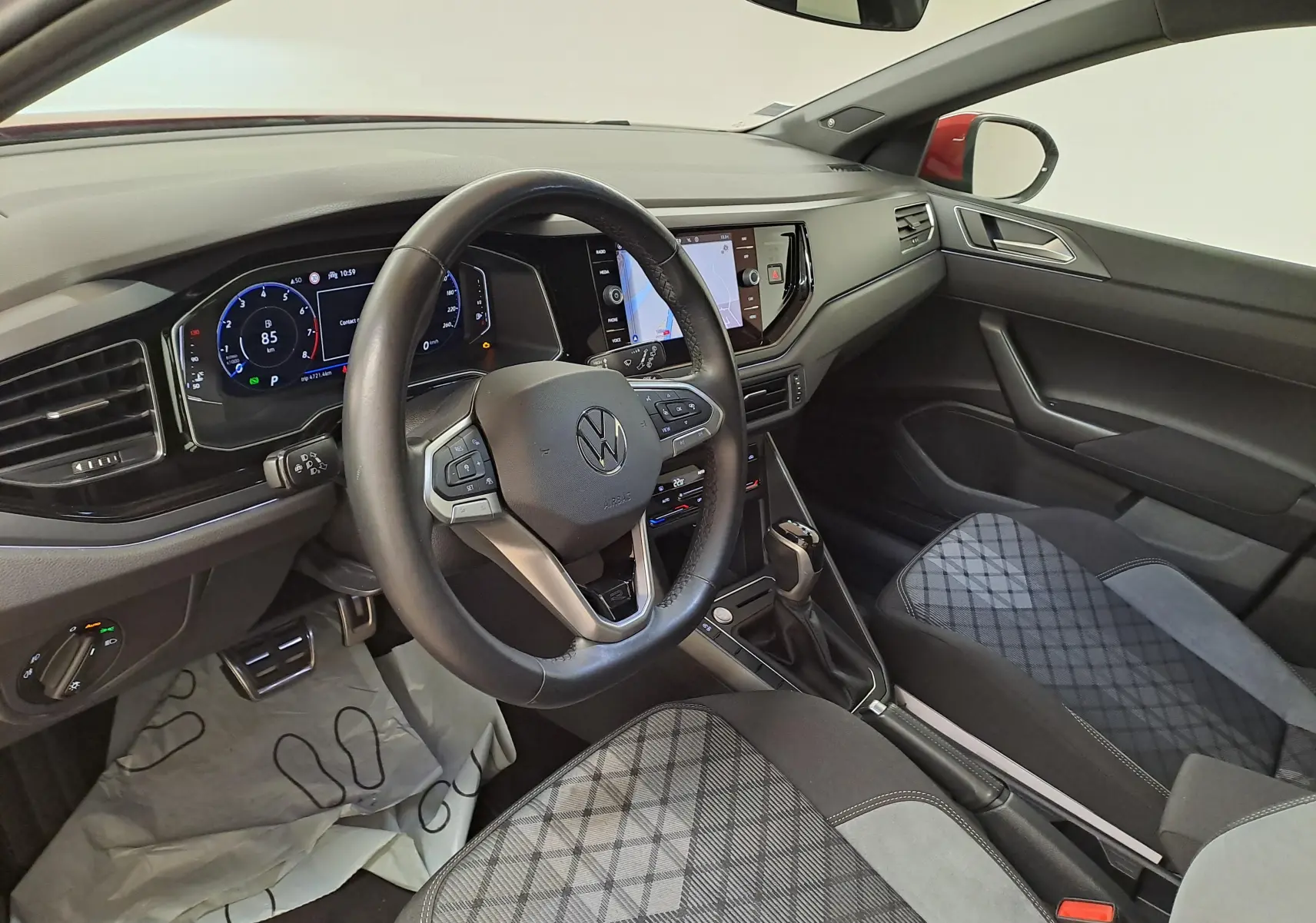 Vue intérieure côté conducteur du Volkswagen Taigo 1.5 TSI R-Line 2021, tableau de bord numérique et sièges tissu gris à motifs.