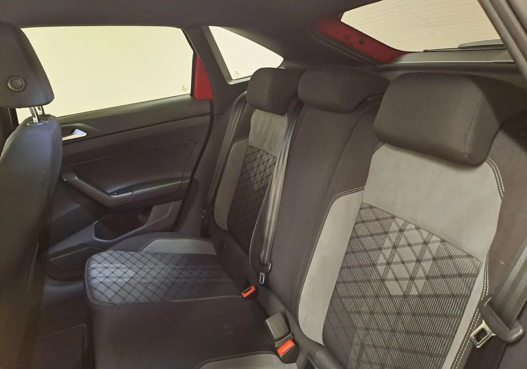 Vue intérieure côté gauche des sièges arrière du Volkswagen Taigo 1.5 TSI Rouge Roi avec sellerie tissu et alcantara à motifs géométriques.