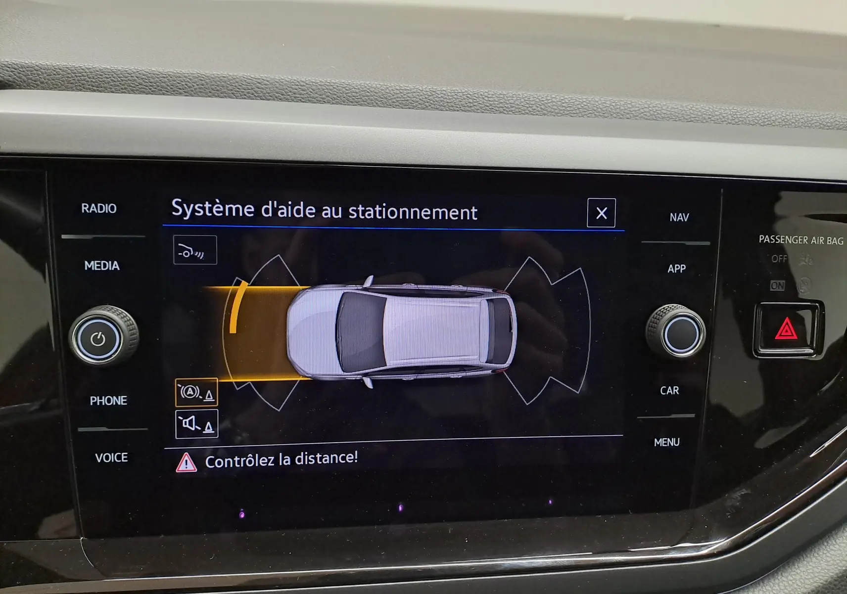 Écran du système d'aide au stationnement affichant une vue du dessus du véhicule avec alerte de distance.