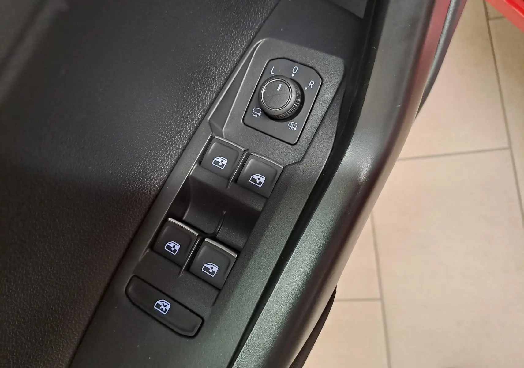 Gros plan sur les commandes de lève-vitres et réglage des rétroviseurs côté conducteur du Volkswagen Taigo Rouge Roi.