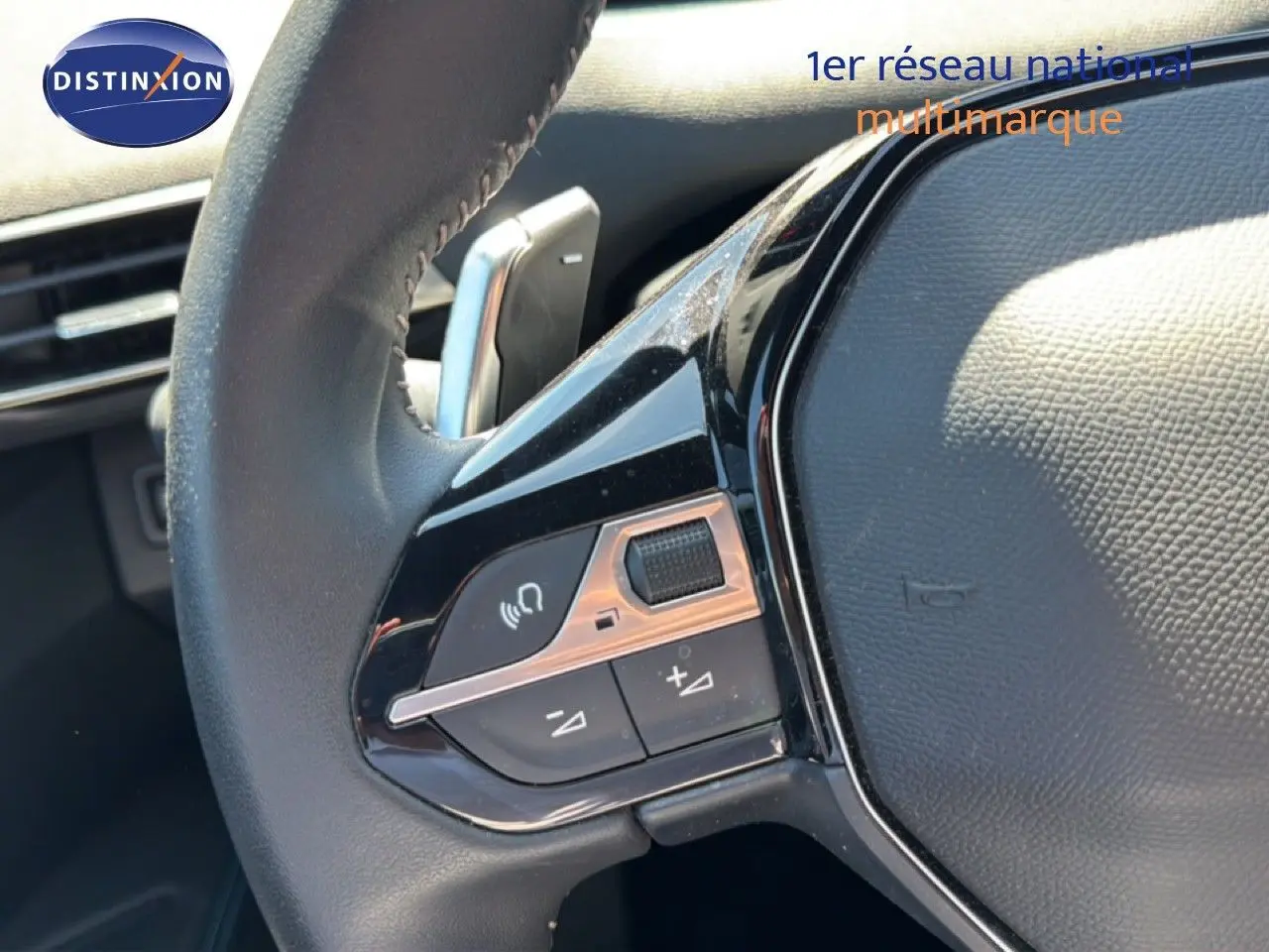 Gros plan sur les commandes gauche du volant cuir du Peugeot 3008 Hybrid 2024, soulignant les boutons multifonctions.