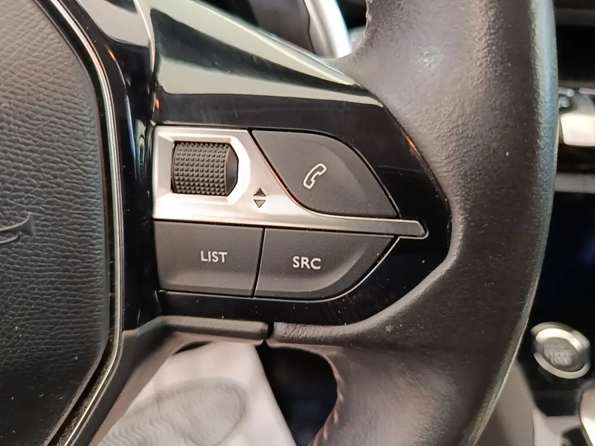 Gros plan sur le côté gauche du volant cuir noir du Peugeot 3008 2022 avec commandes multifonctions et bouton appel.