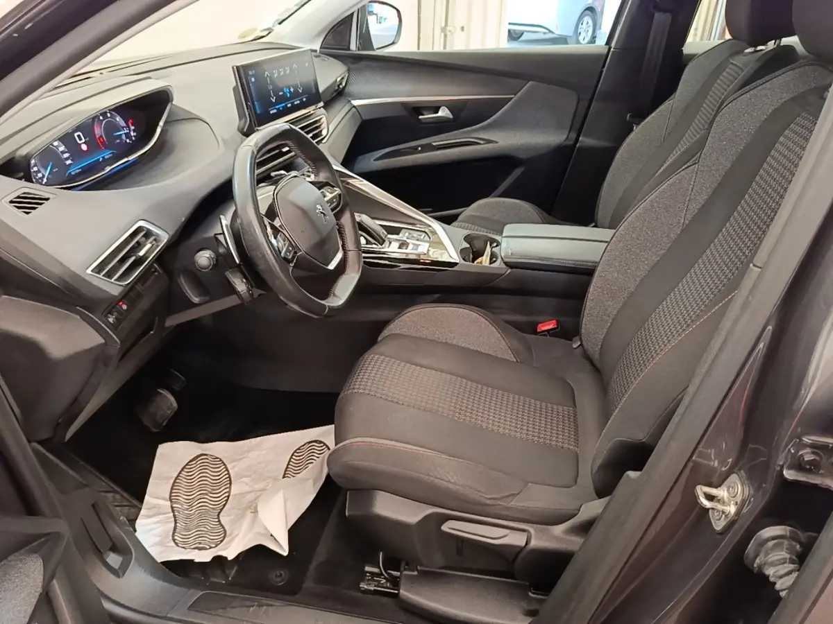 Vue intérieure côté conducteur du Peugeot 3008 gris foncé, volant cuir multifonctions et tableau de bord digital.