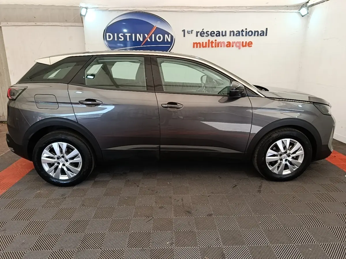 Profil côté droit d’un Peugeot 3008 gris foncé 2022 garé en intérieur avec jantes alliage et toit blanc.