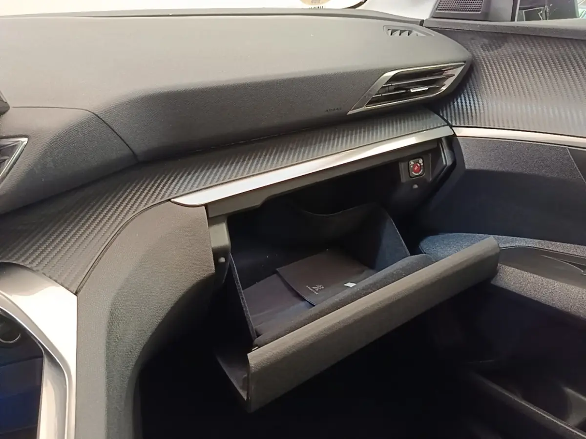 Intérieur du Peugeot 3008 2022, vue côté passager sur la boîte à gants ouverte avec tableau de bord gris foncé.