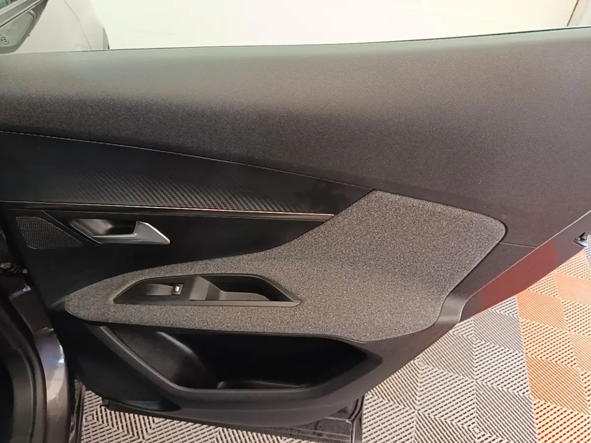 Vue rapprochée de la porte intérieure côté gauche du Peugeot 3008 gris foncé, avec habillage tissu et plastique.