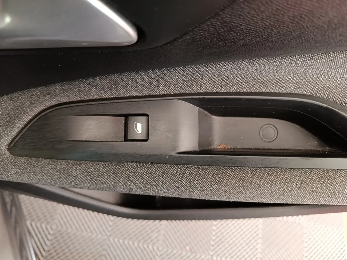 Gros plan sur le bouton de commande de lève-vitre côté conducteur dans l'habitacle gris foncé du Peugeot 3008 2022.