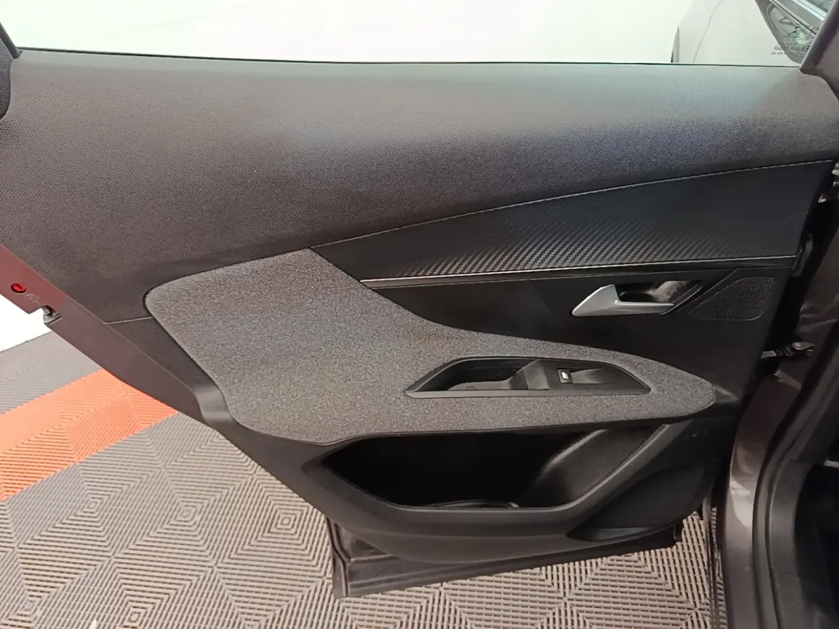 Vue intérieure côté gauche de la porte avant d’un Peugeot 3008 gris foncé, avec habillage tissu et plastique noir.