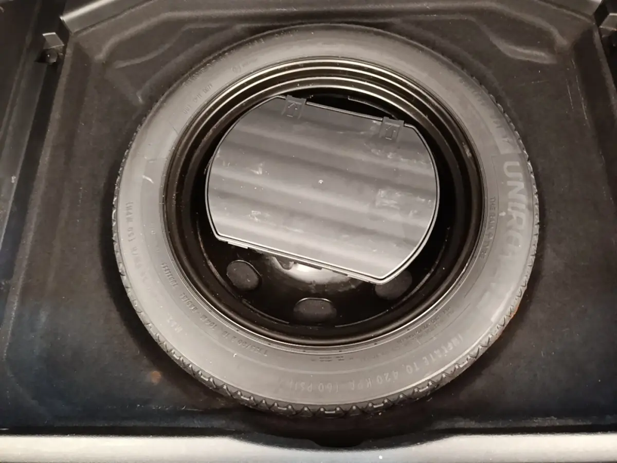 Vue plongeante sur la roue de secours noire dans le coffre d’un Peugeot 3008 gris foncé.