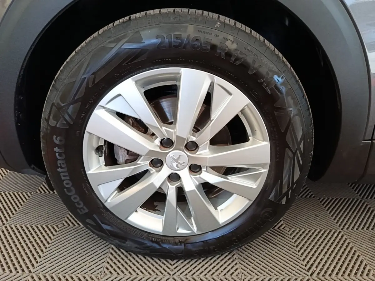 Gros plan sur la roue avant droite du Peugeot 3008 gris foncé avec jante alliage et logo Peugeot central.