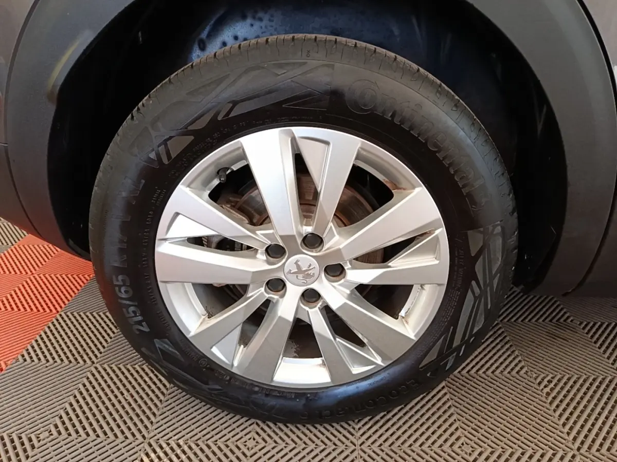 Gros plan sur la roue avant droite avec jante alliage argentée du Peugeot 3008 gris foncé 2022.