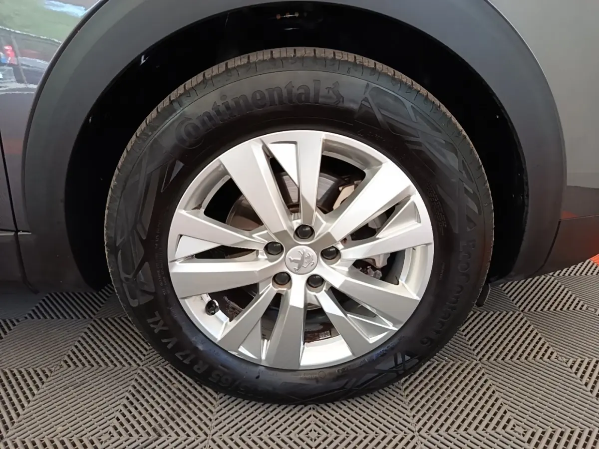Gros plan sur la roue avant droite du Peugeot 3008 gris foncé, mettant en valeur la jante alliage et le pneu Continental.