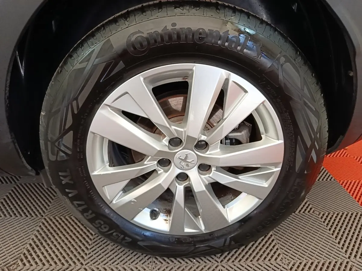 Gros plan sur la roue avant droite d’un Peugeot 3008 gris foncé avec jante alliage et pneu Continental.