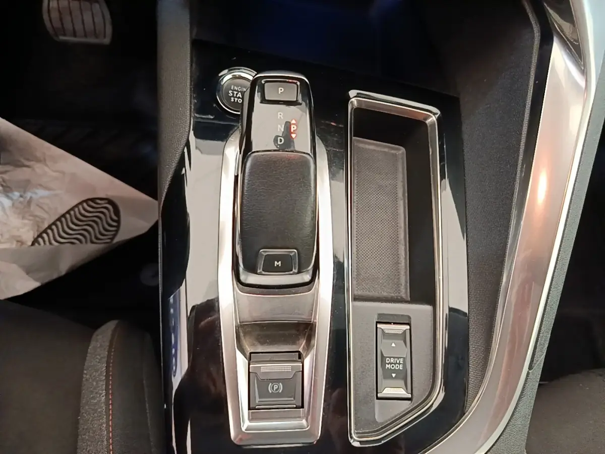 Vue rapprochée de la console centrale noire brillante du Peugeot 3008 2022 avec levier de boîte auto et bouton Drive Mode.