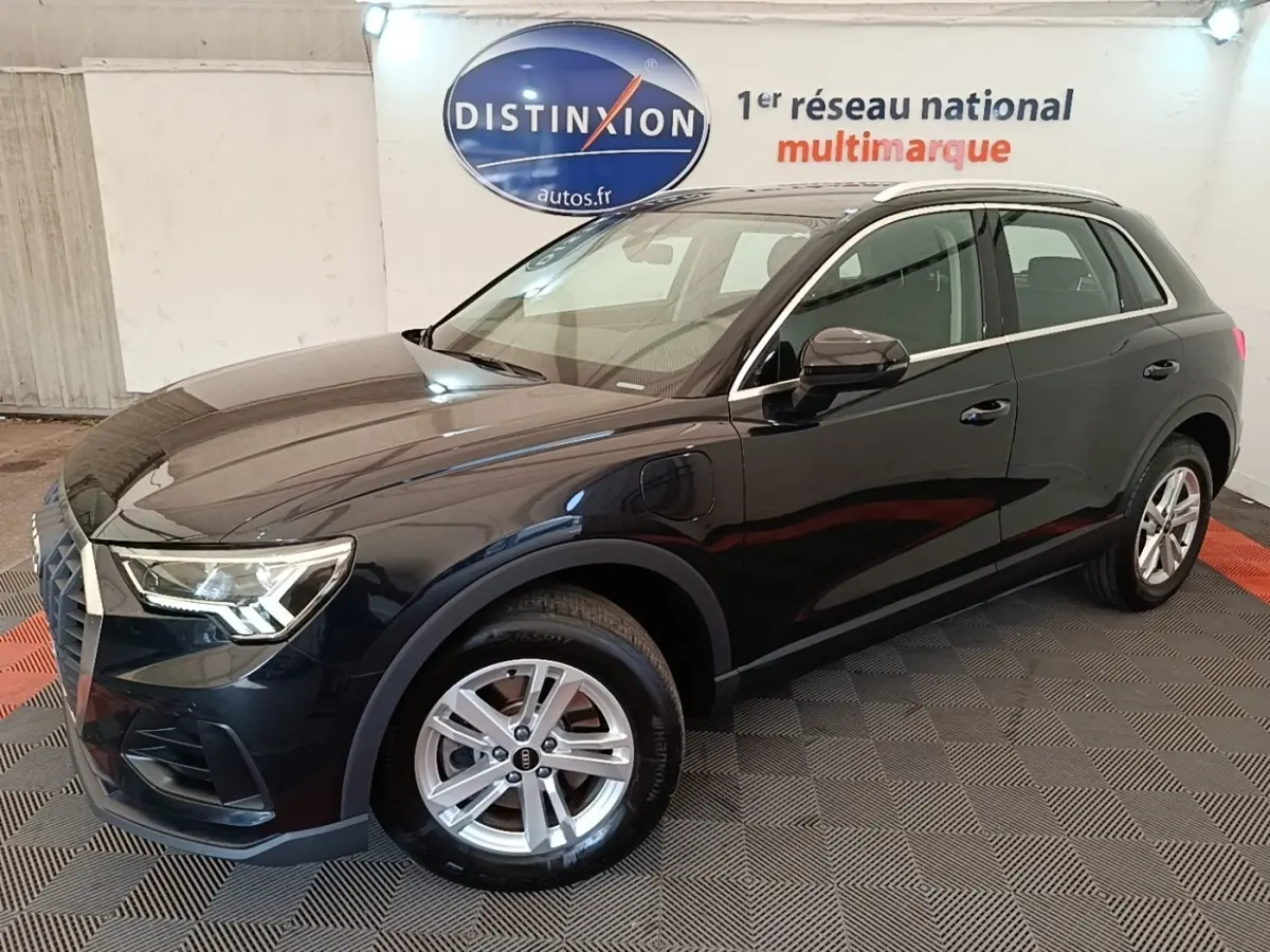 Audi Q3 hybride rechargeable 2023 vue 3/4 avant droit, carrosserie noire brillante avec jantes argentées et phares LED.