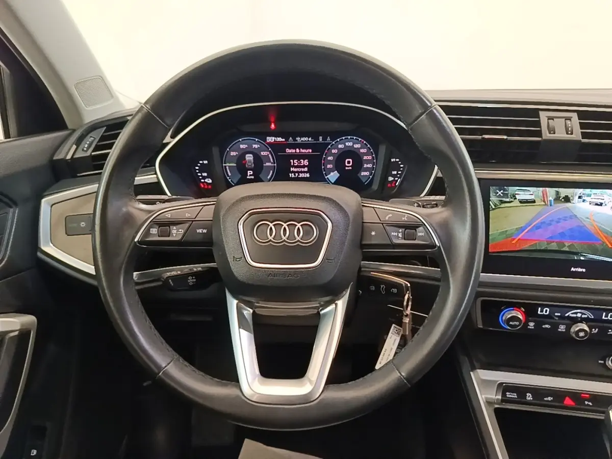 Vue intérieure centrée sur le volant cuir multifonctions noir et le tableau de bord digital de l'Audi Q3 hybride rechargeable 2023.
