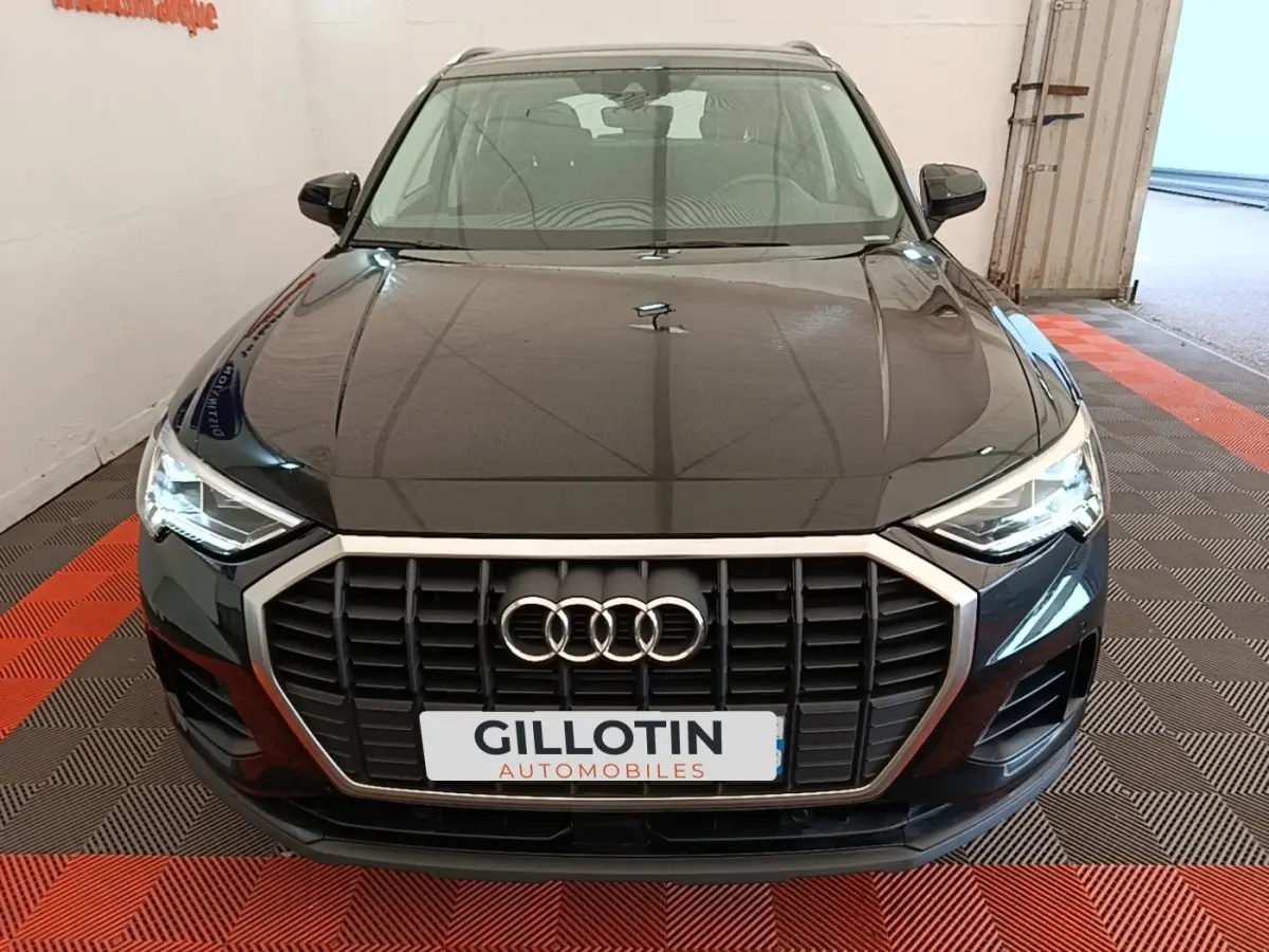 Vue avant d'un Audi Q3 45 TFSI e hybride rechargeable noir avec calandre large et phares LED allumés.