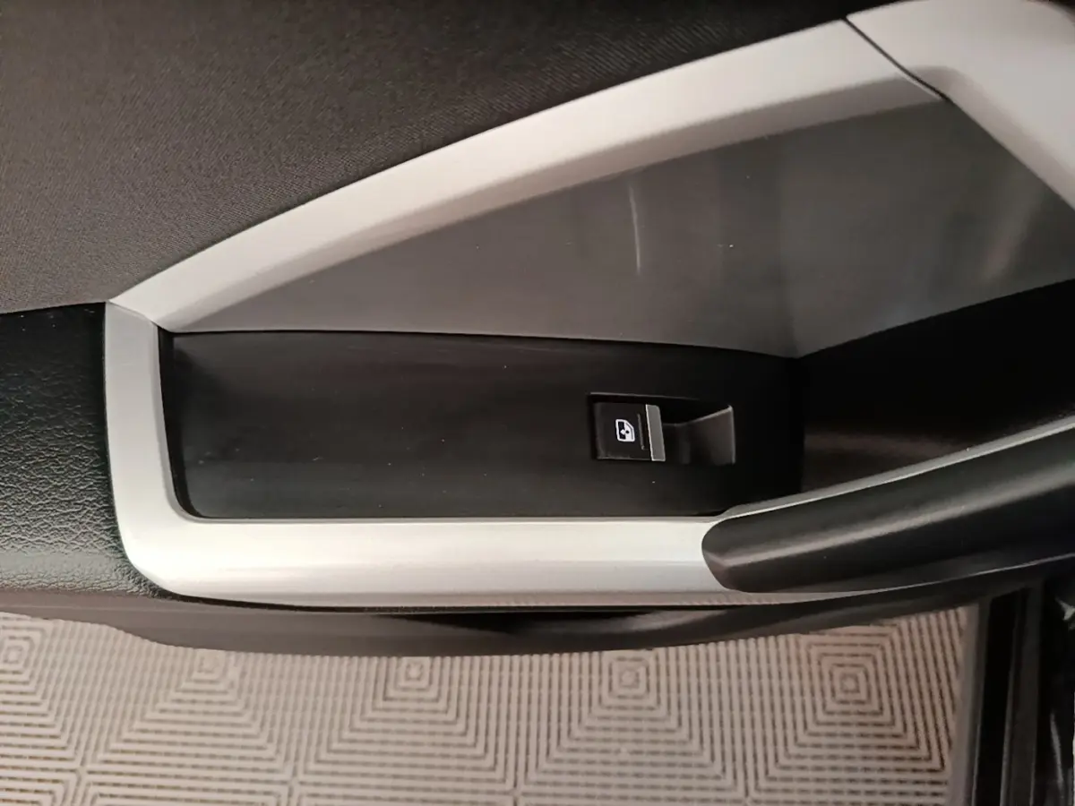 Détail de la commande de lève-vitre côté gauche intérieur de l'Audi Q3 45 TFSI e 2023 avec insert argenté.