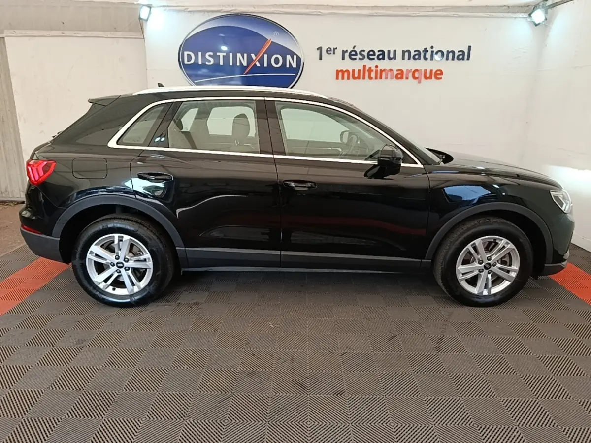 Vue latérale droite d'un Audi Q3 45 TFSI e hybride rechargeable noir, avec jantes alliage et rails de toit chromés.