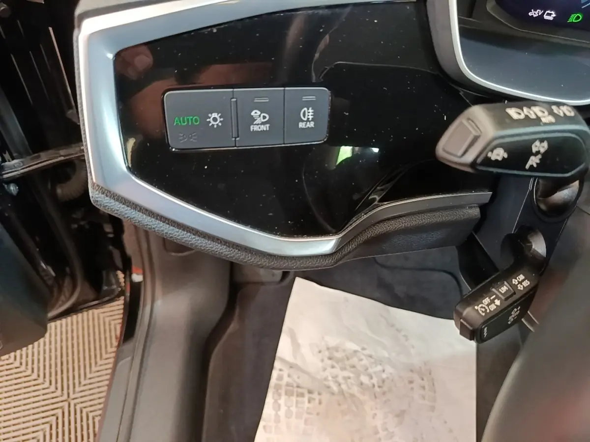 Détail du tableau de bord noir brillant côté gauche avec commandes d’éclairage sur Audi Q3 hybride 2023.
