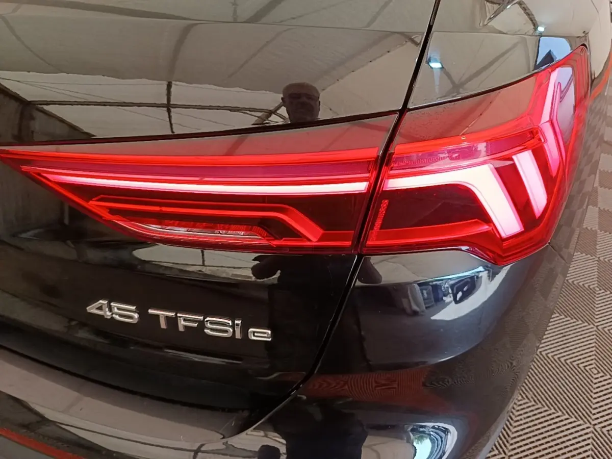Gros plan sur le feu arrière droit rouge d’un Audi Q3 hybride rechargeable noir avec badge 45 TFSI e.