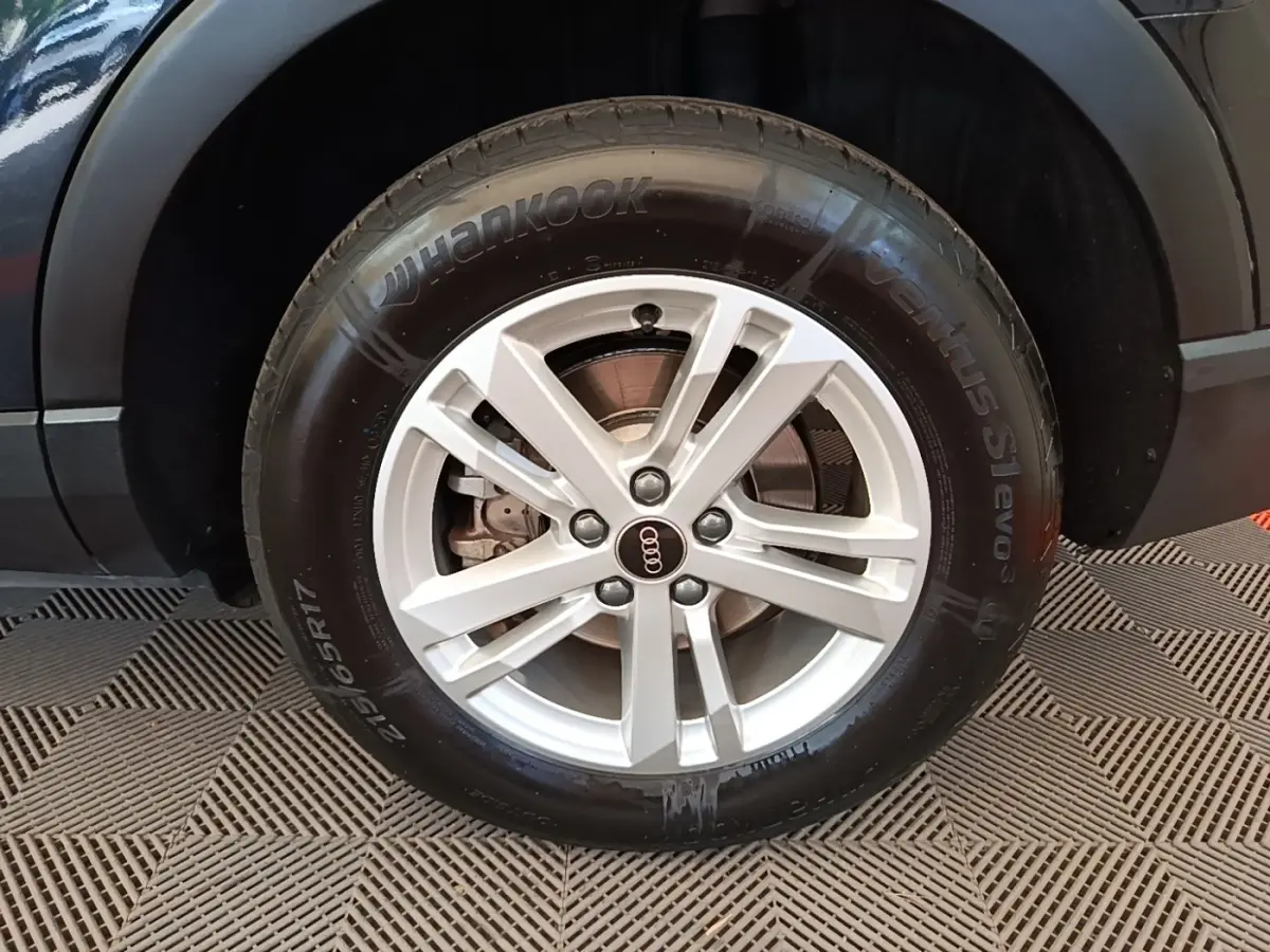 Gros plan sur la roue avant droite argentée d’un Audi Q3 45 TFSI e 245 S tronic Business Line, carrosserie noire.