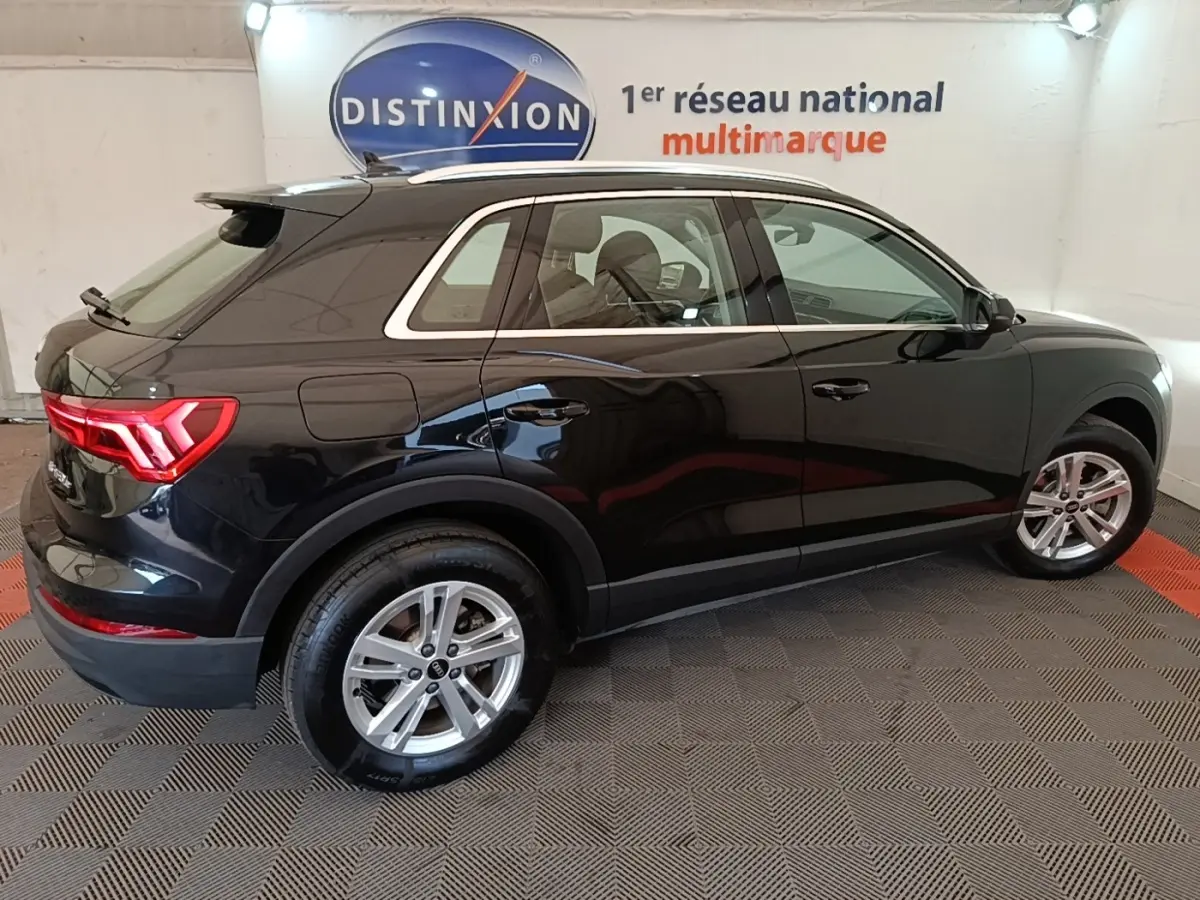 Audi Q3 hybride rechargeable noir vue de profil côté droit en intérieur avec jantes alliage et feux arrière LED allumés.