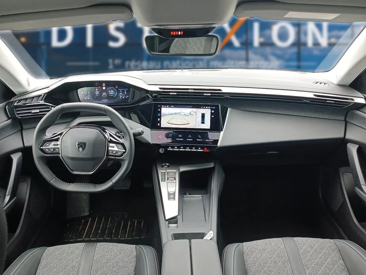 Intérieur Peugeot 408 Hybrid 2024 vu de face, tableau de bord moderne avec écran tactile et volant cuir multifonction.