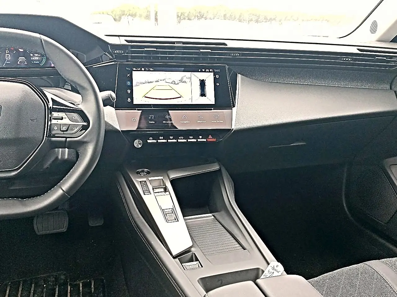 Vue intérieure avant du tableau de bord et console centrale de la Peugeot 408 Hybrid 145 allure, avec écran tactile et volant cuir multifonction.