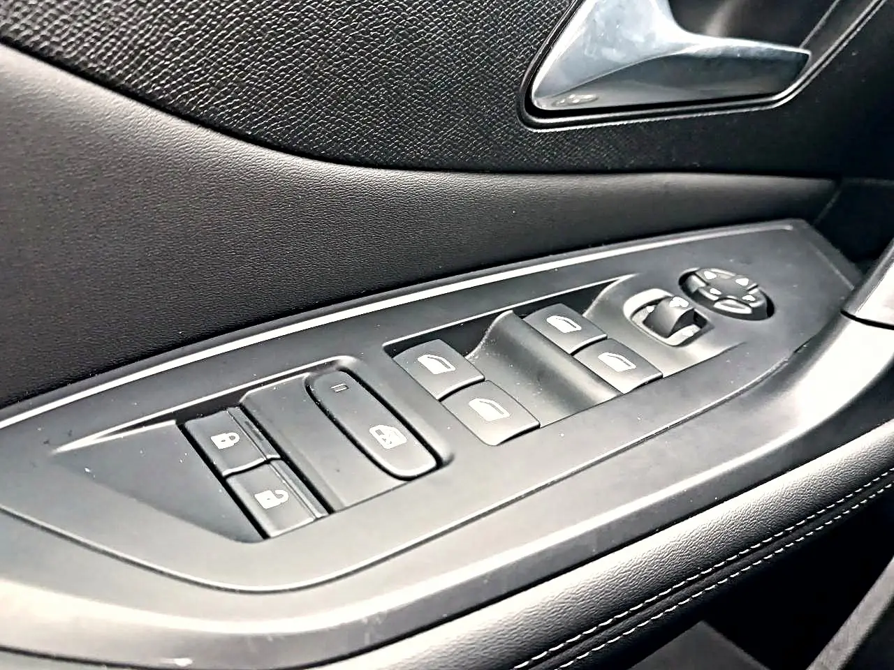 Gros plan sur la commande des vitres et rétroviseurs côté gauche en noir à l'intérieur d'une Peugeot 408 Hybrid 145 allure 2024.