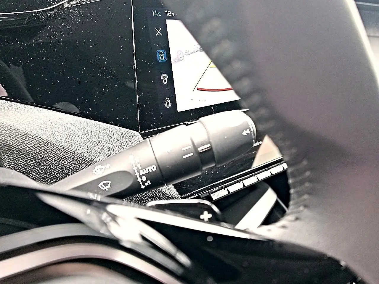 Gros plan sur la commande d’essuie-glace et l’écran tactile du tableau de bord d’une Peugeot 408 Hybrid 145 gris sélénite.