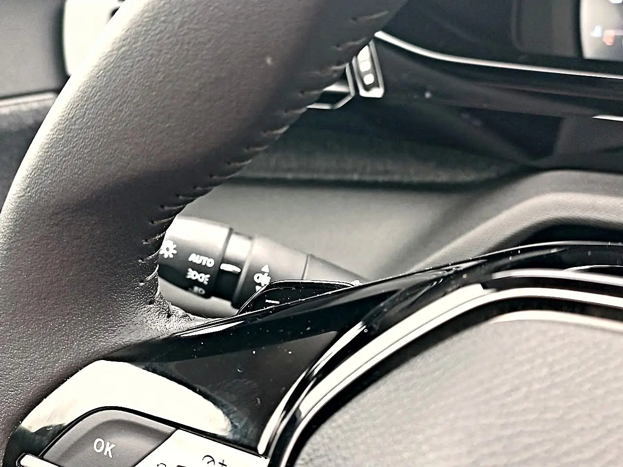Gros plan sur le volant cuir noir multifonction de la Peugeot 408 Hybrid 145 allure, avec commandes au volant visibles.
