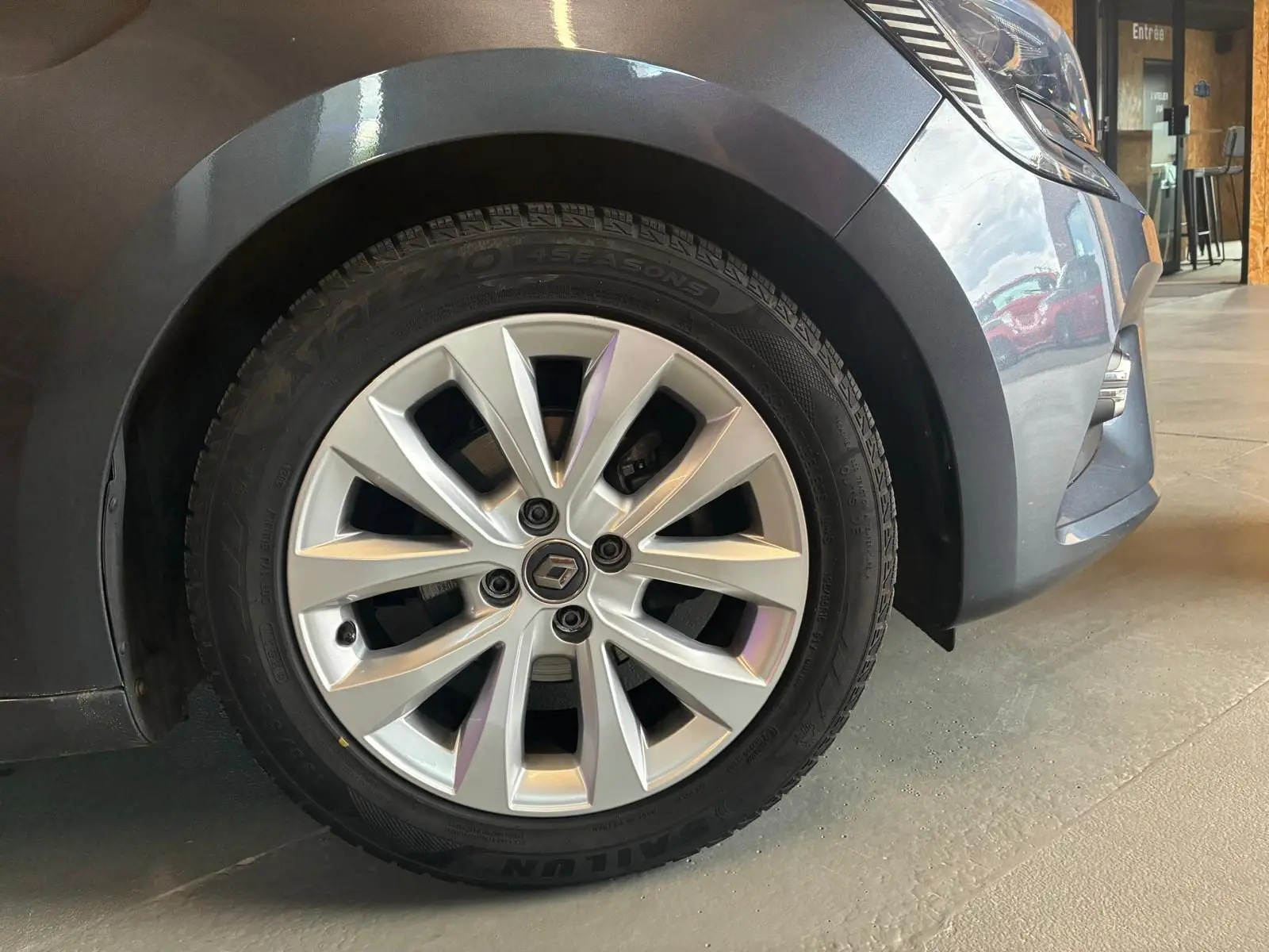 Gros plan sur la roue avant gauche grise d'une Renault Clio 1.0 TCE 100 Intens avec jante alliage moderne.