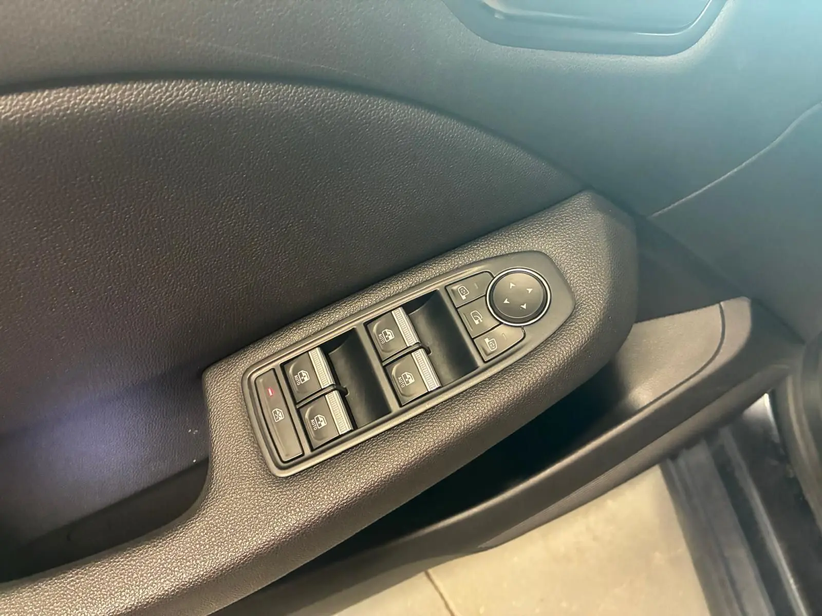 Gros plan sur la commande des vitres côté conducteur d'une Renault Clio gris 2020 avec intérieur tissu gris-noir.