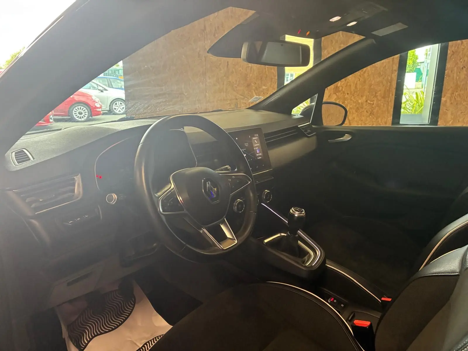 Vue intérieure côté conducteur de la Renault Clio gris 2020, volant multifonction et levier de vitesse manuel visibles.