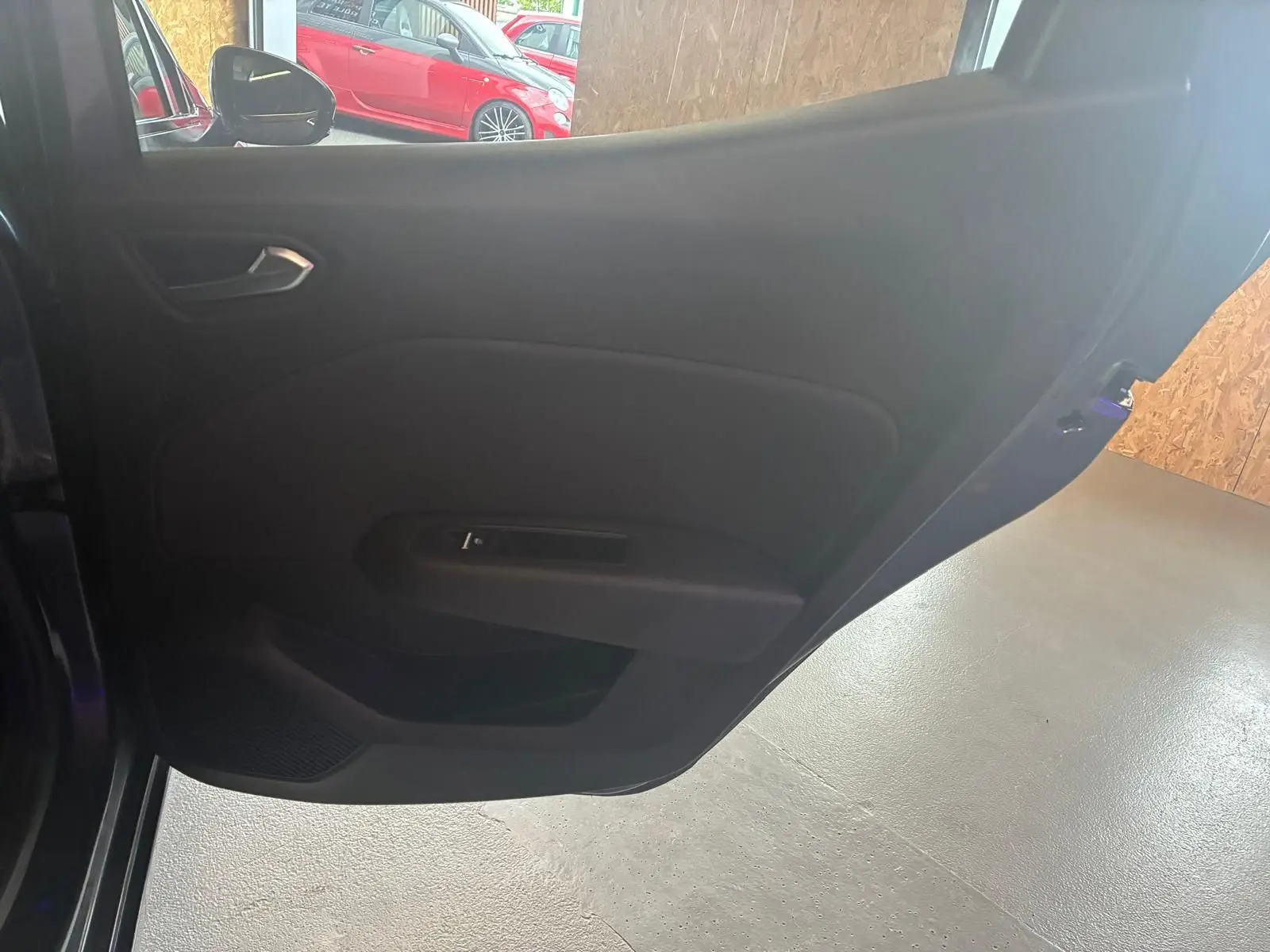 Vue intérieure de la porte arrière gauche d'une Renault Clio gris 2020 avec poignée et panneau noir simple.