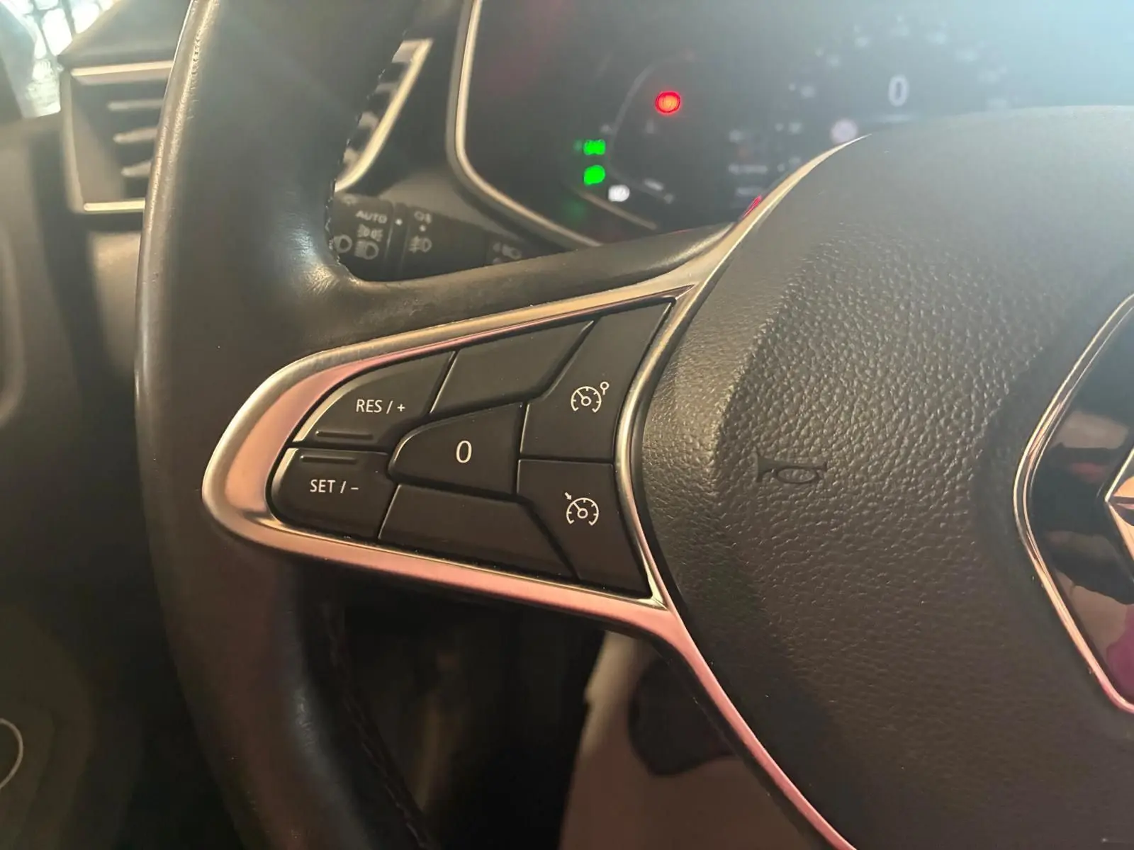 Gros plan sur les commandes de régulateur de vitesse du volant cuir noir d'une Renault Clio gris 2020.