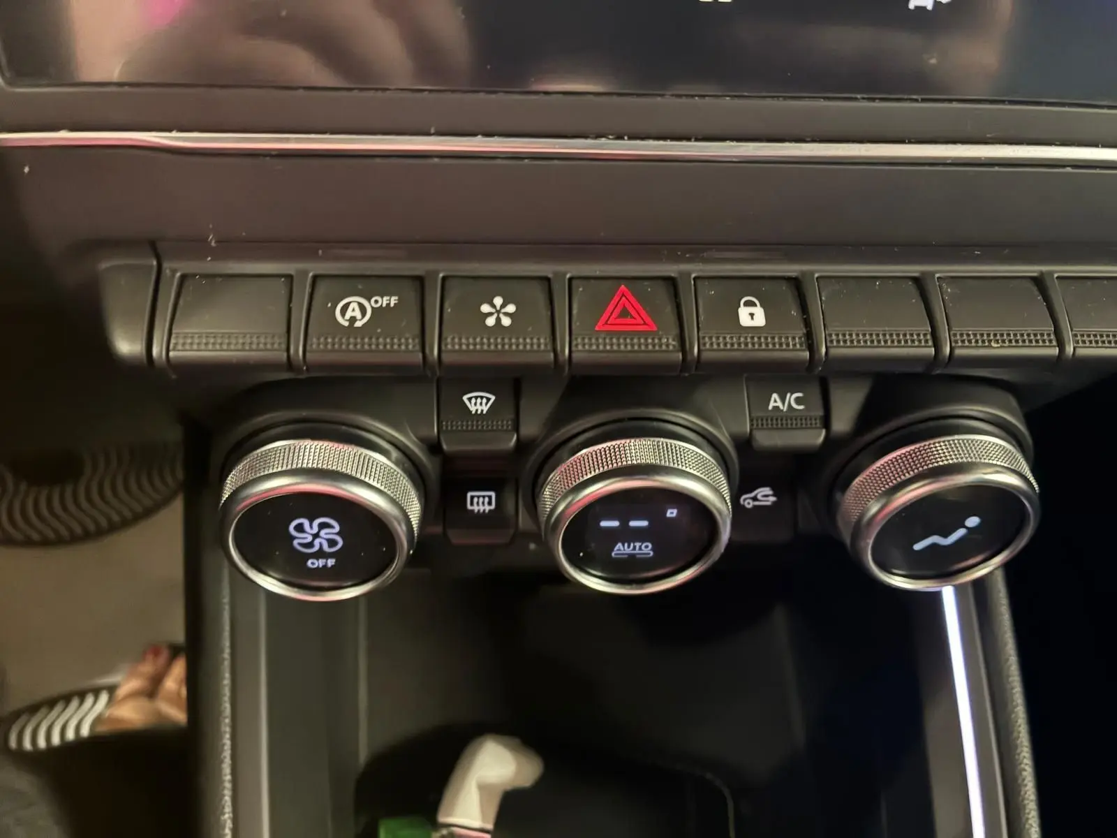 Détail des commandes de climatisation et boutons de sécurité sur la console centrale d'une Renault Clio gris 2020.