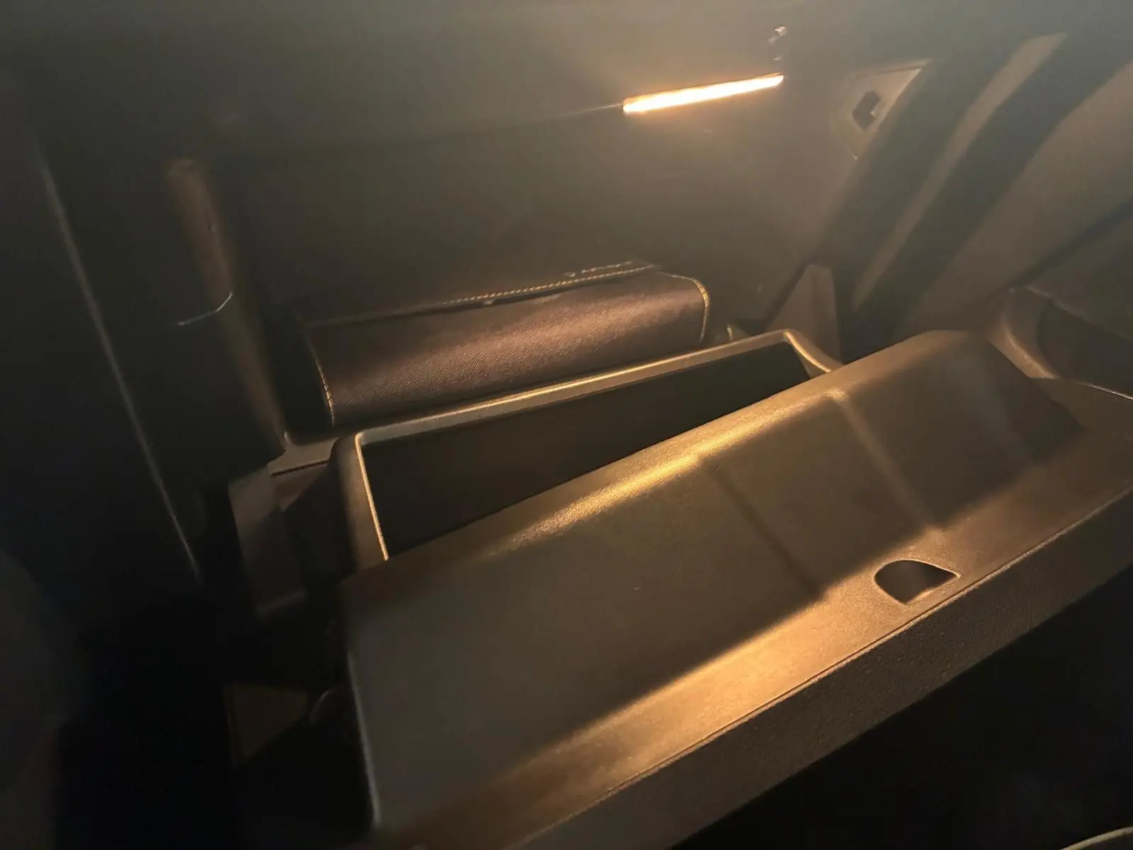 Gros plan sur la boîte à gants ouverte de la Renault Clio gris 2020, éclairage intérieur tamisé mettant en valeur le rangement.