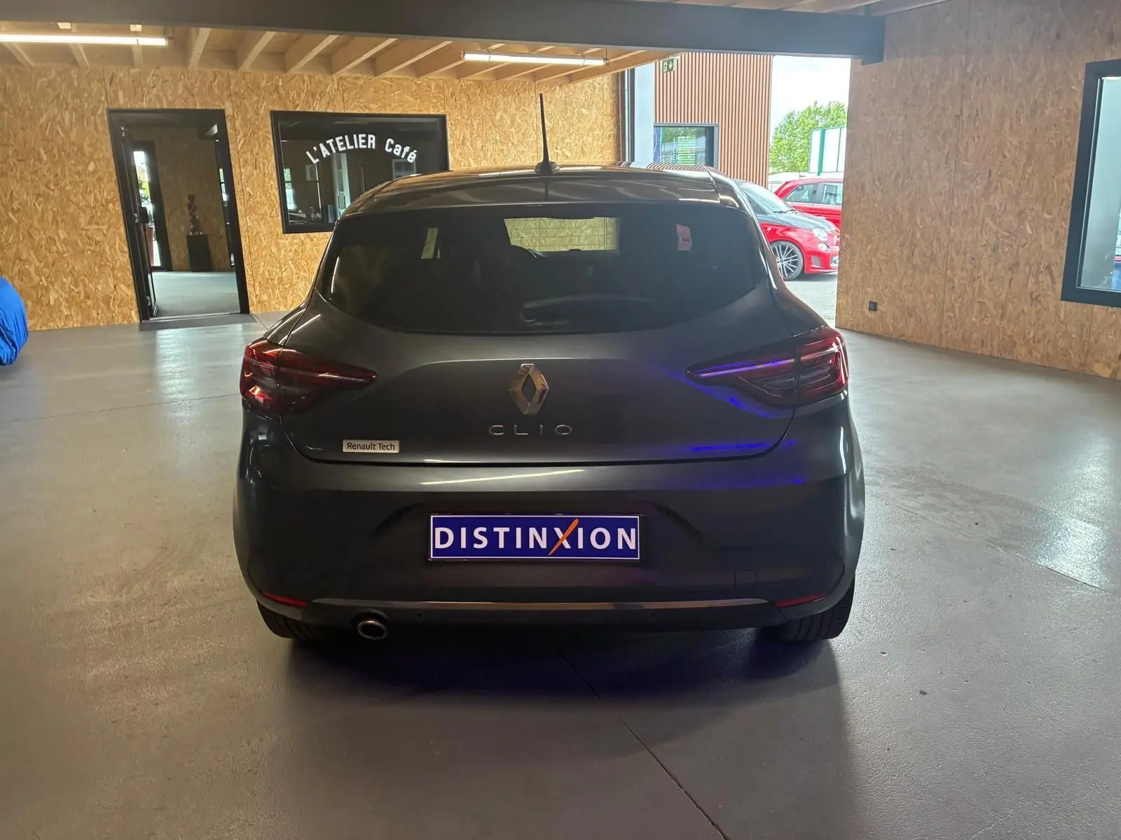 Vue arrière d'une Renault Clio gris foncé 2020, avec logo Renault et plaque Distinxion visible en intérieur d'atelier.