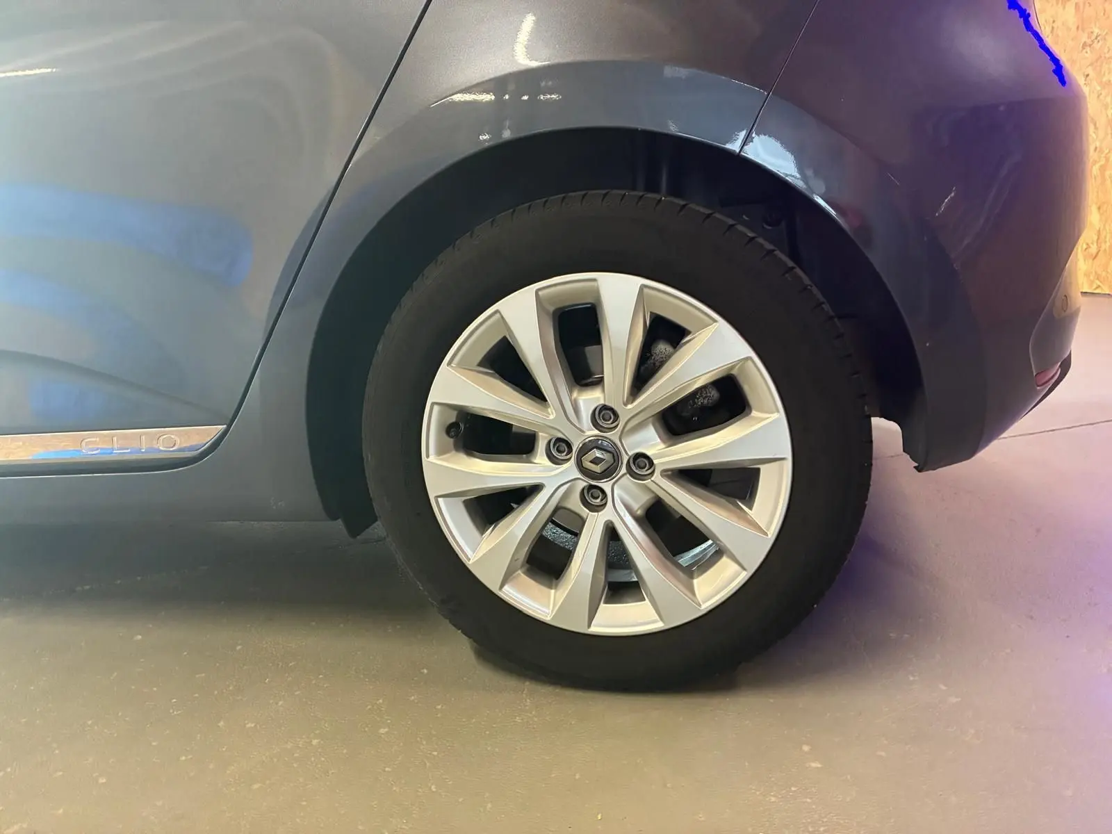 Gros plan sur la roue arrière droite gris métallisé d'une Renault Clio 1.0 TCE 100 Intens avec jante alliage et logo Renault.